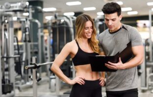 Mulher acompanhando a explicação do personal sobre o seu treino em academia de Moema