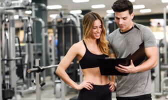 Mulher acompanhando a explicação do personal sobre o seu treino em academia de Moema