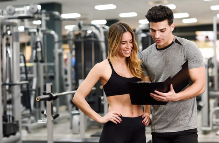 Mulher acompanhando a explicação do personal sobre o seu treino em academia de Moema